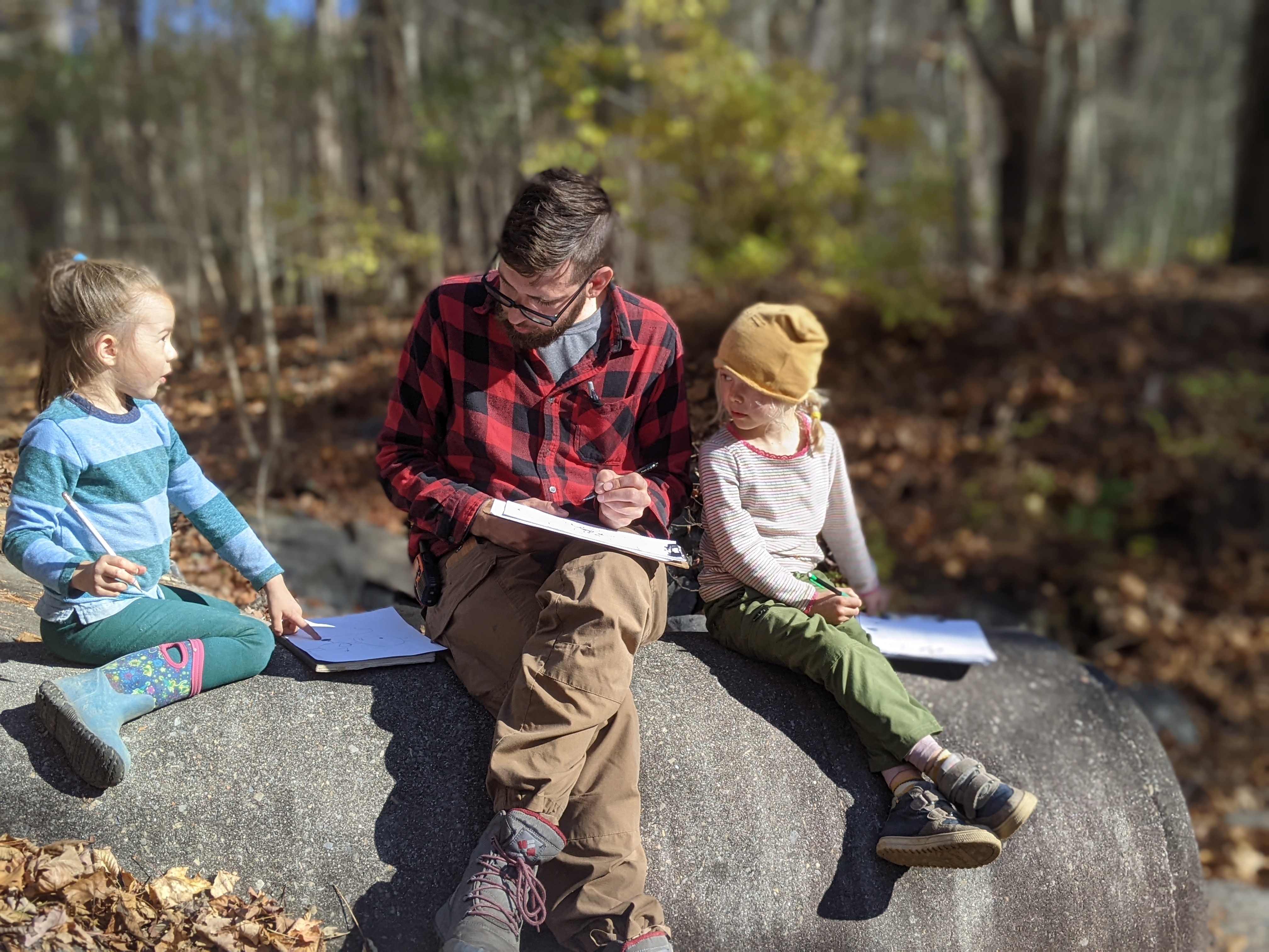 children and adult on rocks with notepads critter chats